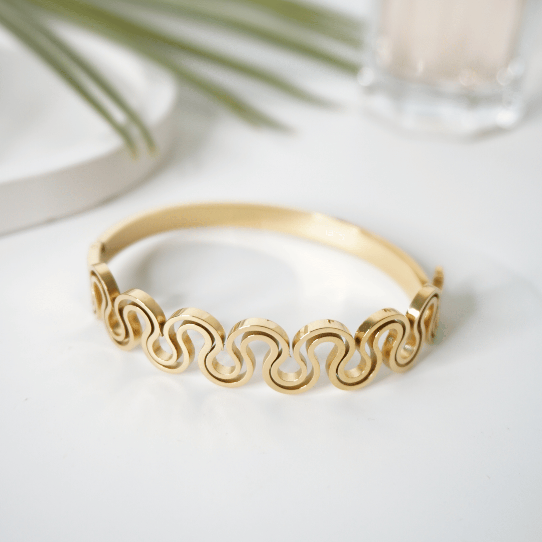 Gold bracelet with wave pattern on a light background